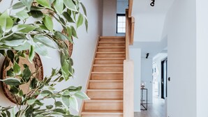 Una escalera de madera que conduce a un segundo piso, rodeada de paredes blancas y piso de madera.