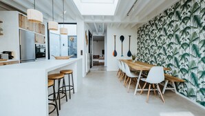 Una cocina moderna con una isla central, armarios blancos e iluminación colgante.
