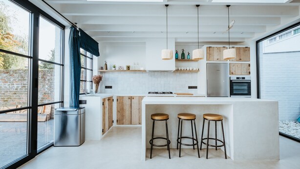 Una cocina moderna con una isla grande, taburetes de bar e iluminación colgante.