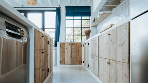 Una cocina estrecha con armarios de madera y una ventana con cortinas azules.