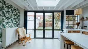 Cocina moderna con una isla grande, una silla de mimbre y vistas al patio trasero a través de puertas de vidrio.