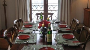 A dining room with a long table set for six, featuring red plates, wine glasses, and a candle centerpiece. - Luxury alpine apartment with warm indoor pool, sauna & fitness room (Gstaad)