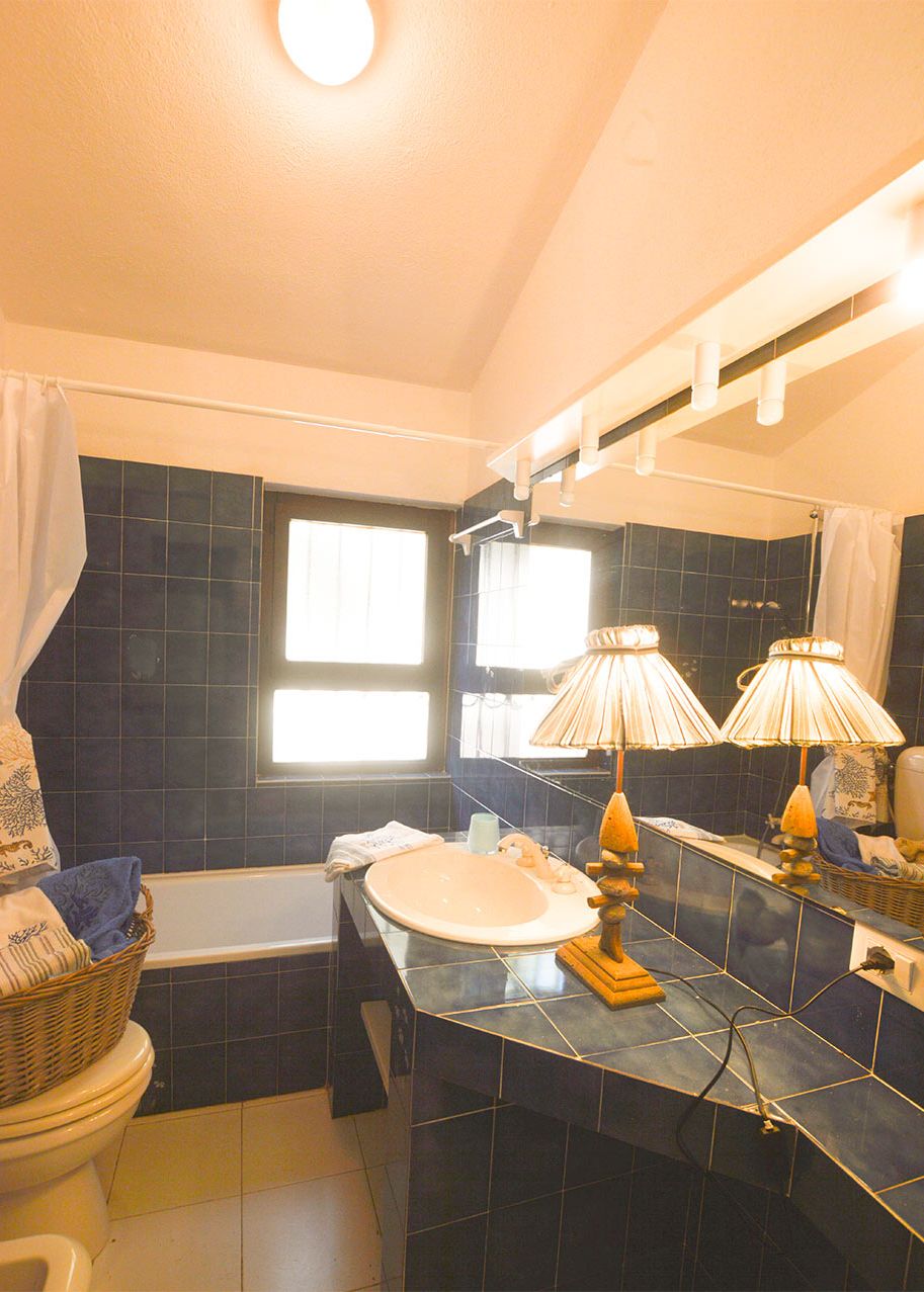Ein Badezimmer mit Badewanne, Toilette und Waschbecken. Auf der Ablage befinden sich zwei Lampen.
