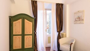 Ein Zimmer mit einem grünen Schrank, einem weißen Stuhl und einer mit Vorhängen versehenen Tür.