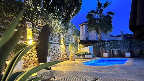 An outdoor pool area with lounge chairs, a stone wall, and potted plants. - Villa on Mar Menor Golf Resort, Murcia. High quality 3-bed villa with pool. (Torre-Pacheco)