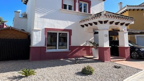 A two-story building with a white facade and red accents, featuring a covered entrance and a visible garage. - Villa on Mar Menor Golf Resort, Murcia. High quality 3-bed villa with pool. (Torre-Pacheco)