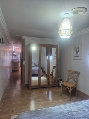 Un corridoio che porta a una camera da letto con una porta in legno, una sedia e un piccolo tavolo.
