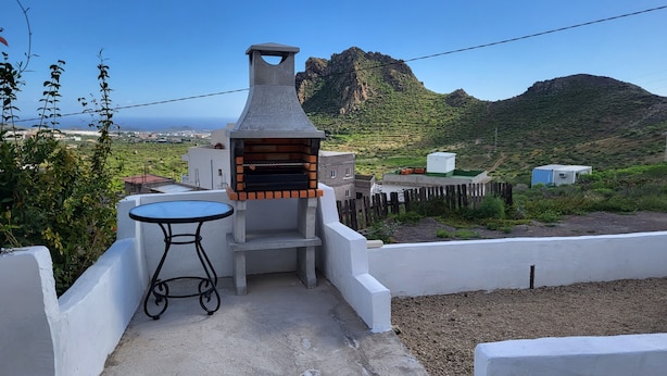 A patio with a barbecue grill, a table, and a view of a mountainous landscape. - Sandra's house  (Arona)