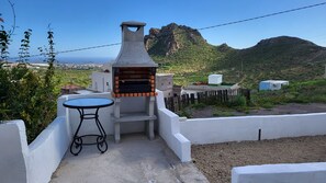 A patio with a barbecue grill, a table, and a view of a mountainous landscape. - Sandra's house (Arona)