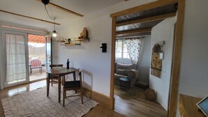 A dining area with a table and chairs, a hanging light fixture, and a view through a glass door to an outdoor patio. - Sandra's house  (Arona)