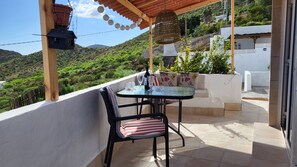 A balcony with a table and chairs, overlooking a green hillside. - Sandra's house  (Arona)