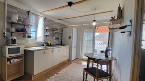 A kitchen with white cabinets, a microwave, a refrigerator, and a dining area with a table and chairs. - Sandra's house  (Arona)