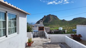 A small outdoor patio with a barbecue grill, potted plants, and a view of a mountainous landscape. - Sandra's house  (Arona)