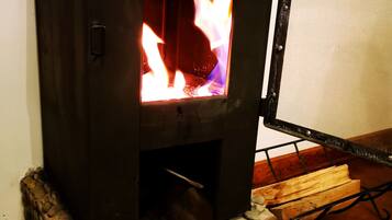 A wood-burning stove with a stone base and a metal grate.