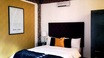 A hotel room with a large bed, a map on the wall, and an air conditioning unit.