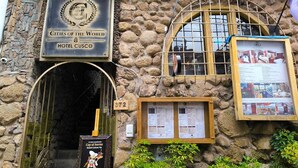 A stone building with a sign for Hotel Cusco, a wooden door, and a menu board. - Cities of the World - Apartments Cusco (Cusco)