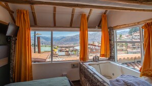 A room with a large window, a bathtub, and a bed. - Cities of the World - Apartments Cusco (Cusco)