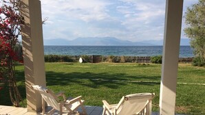 A patio with two wooden chairs facing a grassy area and a view of the sea. -  Our small seafront paradise !!! (Akrata)
