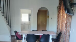 Ein Essbereich mit Tisch und Stühlen, einem an der Wand montierten Fernseher und einer Treppe.