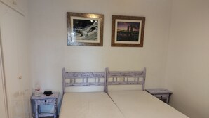 Ein Schlafzimmer mit einem Einzelbett, einem Nachttisch, einem kleinen Tisch und zwei gerahmten Bildern an der Wand.