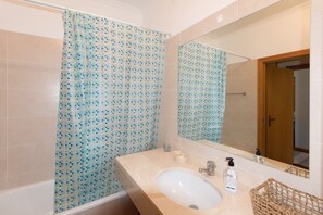 Een bad/douchecombinatie, een bidet, handdoeken