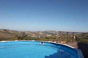 A swimming pool with a wooden deck and a view of rolling hills. - Newly renovated farmhouse with pool - views of the sea and mountains (Crocetta Santa Maria)