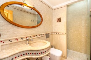Un baño con un espejo redondo, un lavabo y un inodoro.