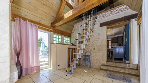Ein geräumiges Zimmer mit hoher Decke, einer Treppe, einer Küchenzeile und Blick ins Freie.