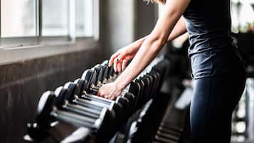 A person using a row of dumbbells in a gym with a window in the background.
