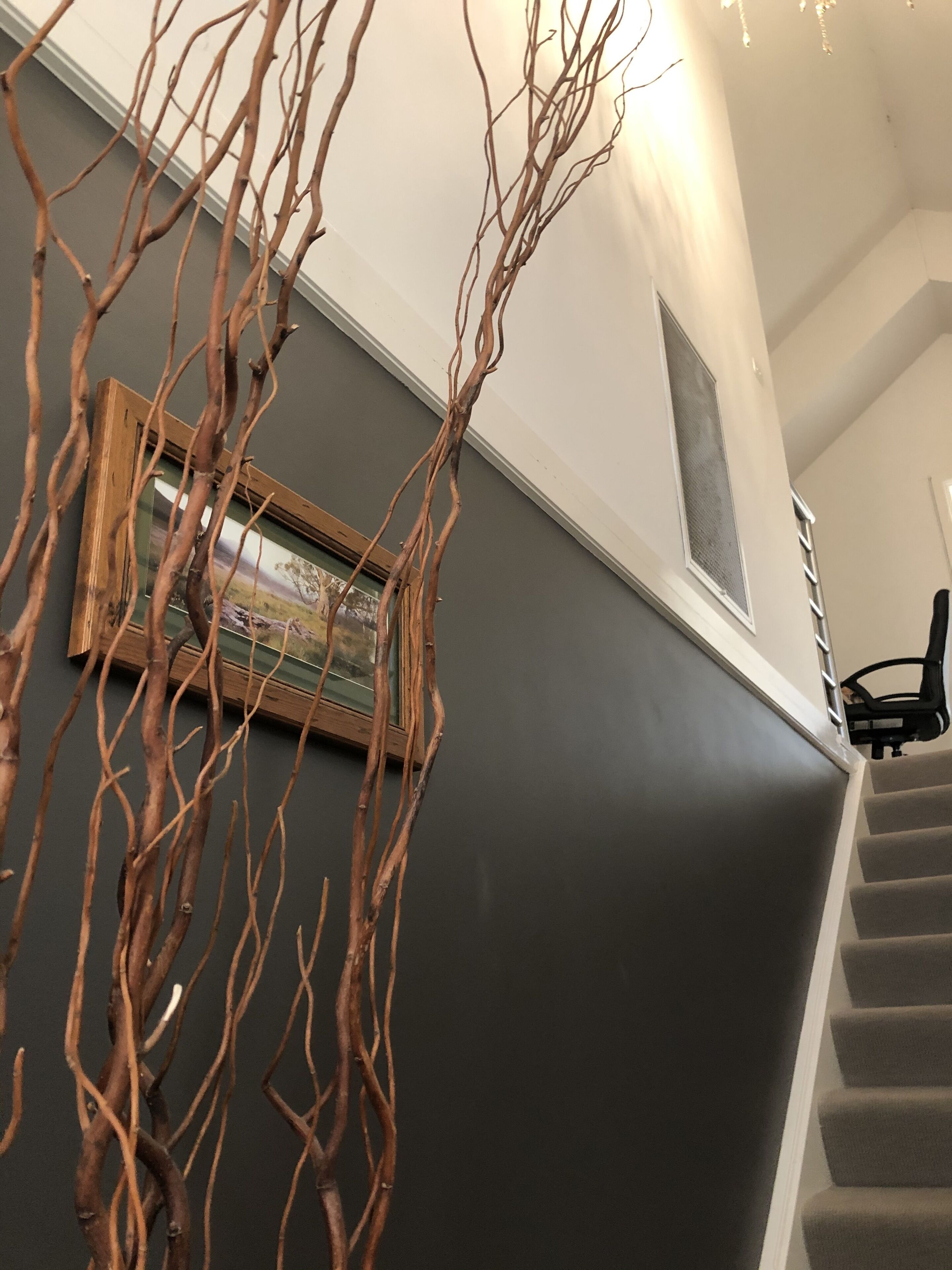 A staircase with a dark wall and a framed picture on the wall.