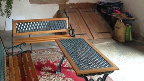 Un intérieur rustique avec un banc en bois, une table en métal et une lanterne fixée au mur.