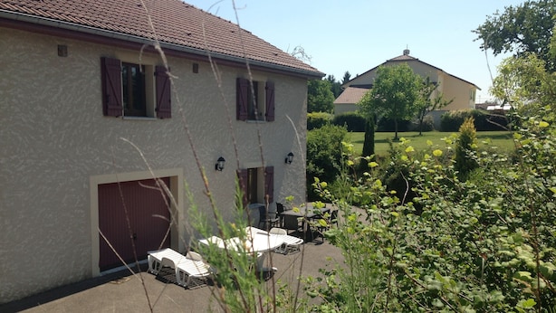 Une maison à deux étages, avec un toit en tuiles, un garage et un patio aménagé avec du mobilier d’extérieur.