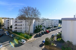 Et boligområde med hvide lejlighedskomplekser, en parkeringsplads og en klar himmel.