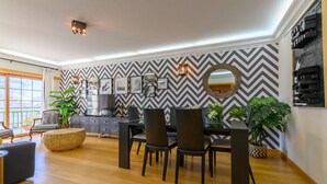 A modern dining area with a black and white chevron-patterned wall, a round mirror, and a dark wooden dining table with chairs. - CARCAVELOS BEACH. A wonderful 2 bedroom apartment (Carcavelos)