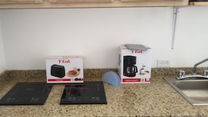 Une cuisine équipée de deux appareils de la marque Tefal : un grille-pain et une machine à café, le tout posé sur un plan de travail en granit.