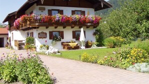 A traditional chalet with a balcony adorned with colorful flowers, a wooden bench outside, and a sign reading "Bar Ristorante".