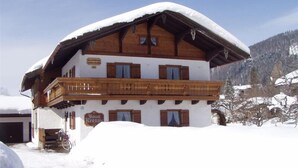 A wooden chalet with a balcony, surrounded by snow.