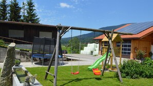 A playground with swings, a slide, and a trampoline.
