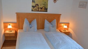 A double bed with a wooden headboard, two bedside tables with lamps, and a painting on the wall.