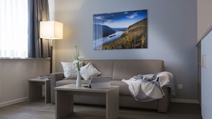 Una sala de estar moderna con un sofá, una mesa de centro, una lámpara y un cuadro en la pared.
