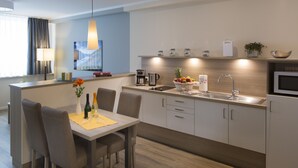 Cocina moderna con comedor, que incluye encimera de madera, lavamanos, cafetera y microondas.