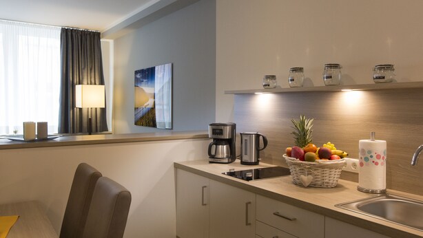 Una cocina moderna con cafetera, hervidor, frutero y soporte para toallas de papel.