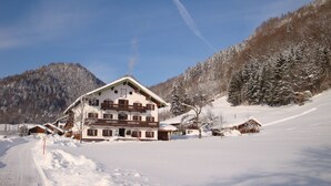 A large, multi-story building with a sloped roof, surrounded by snow-covered trees and a clear sky. - C Apartment Röthelmoos Alm 45sqm, balcony and terrace, 1 bedroom, 1 bedsit. (Ruhpolding)