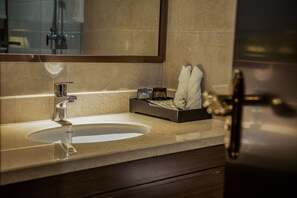 A bathroom with a sink, mirror, and toiletries.