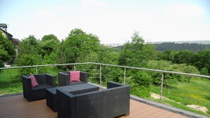 A deck with outdoor furniture and a view of a forested landscape. - Moselle and Hunsrück - Enjoy the wine region and nature (Morbach)