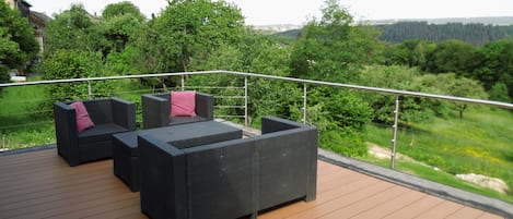 Eine Terrasse mit Gartenmöbeln und Blick auf eine bewaldete Landschaft.