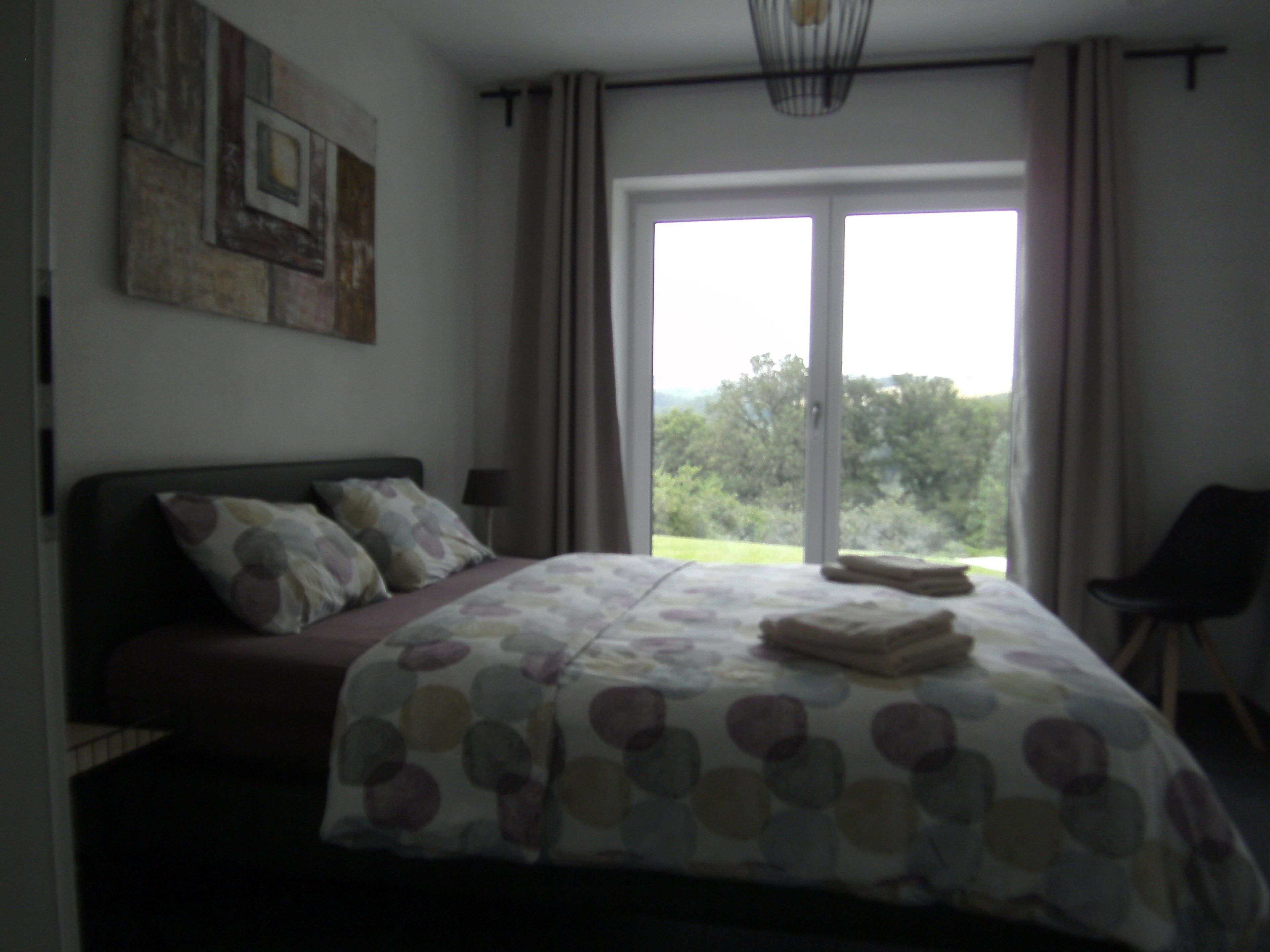 Une chambre à coucher avec un lit, une chaise et une vue sur l’extérieur.