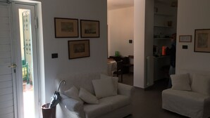 Een woonkamer met een bank, een stoel en een deur naar een balkon.