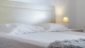 A bed with white linens, a nightstand with a lamp, and a headboard. - Casa da Adega - Holiday Home 2 Minutes from the Beach (Ribeira Chã)
