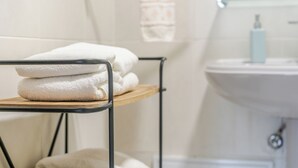A bathroom with a sink, a towel rack with folded towels, and a toilet. - Casa da Adega - Holiday Home 2 Minutes from the Beach (Ribeira Chã)